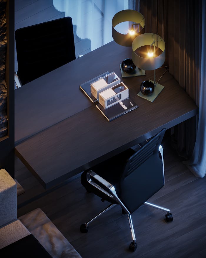 Modern office desk setup with stylish lighting, books, and decor creates a cozy ambiance.